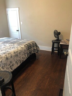 A bedroom with a bed, a chair, a fan, and a door. - Right off of Main St in Robinson (Robinson)