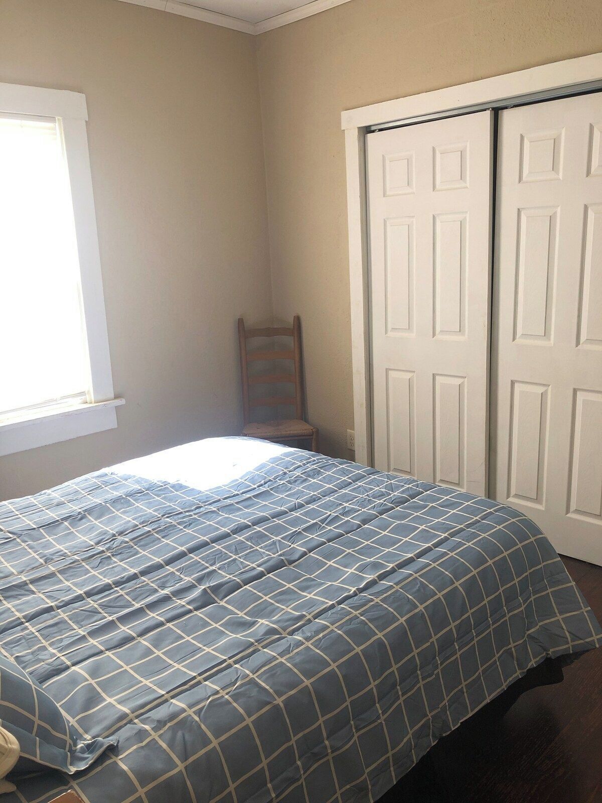 A bedroom with a bed, a chair, and a wardrobe.