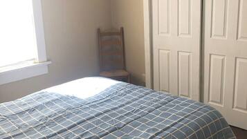 A bedroom with a bed, a chair, and a wardrobe.