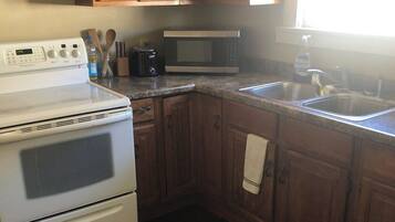 A kitchen with wooden cabinets, a white stove, a microwave, and a sink.