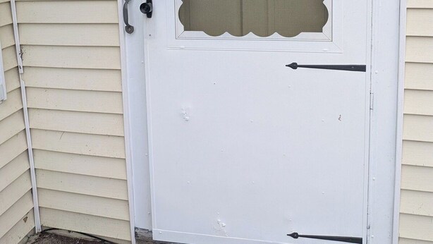A white door with a decorative glass panel and a small mailbox on the wall.
