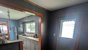 A compact kitchen with dark wood flooring, a central island, and a window with a white blind.