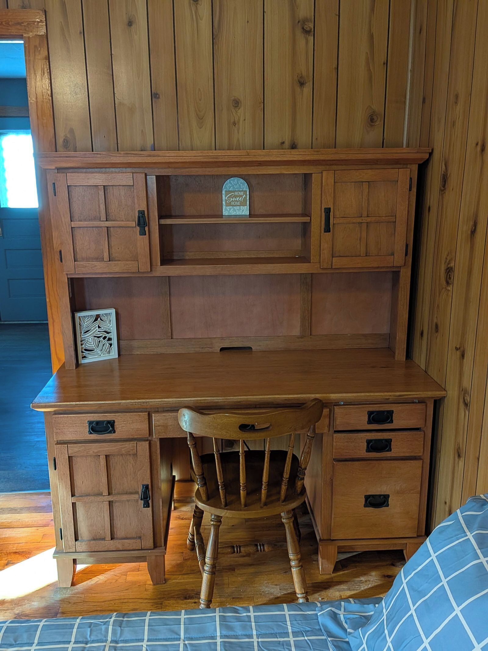Un bureau en bois, doté de tiroirs, et une chaise, dans une pièce aux murs en bois.