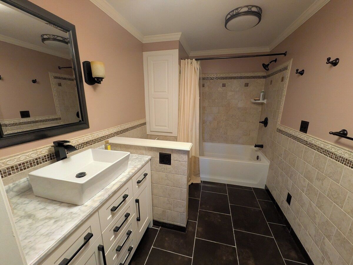 A bathroom with a white sink, a bathtub, and a shower area.