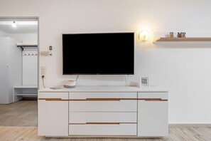 En modern, vit möbel för underhållningssystem, med en platt-TV, ett inbyggt ljudsystem och en hylla med dekorativa föremål.