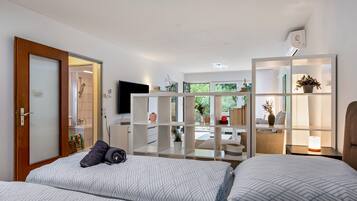 Une chambre à coucher moderne avec un lit, un téléviseur et une bibliothèque intégrée agrémentée de plantes.