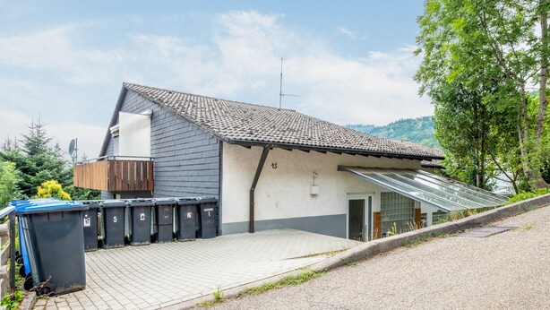 Un edificio residencial con techo inclinado, garaje y entrada pavimentada.