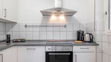 A modern kitchen with a stainless steel range hood, a coffee maker, a kettle, and a toaster.