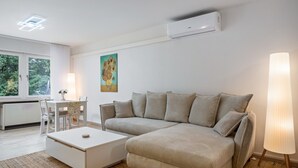 Una sala de estar moderna con un sofá, una mesa de centro, una mesa de comedor con sillas y un cuadro en la pared.