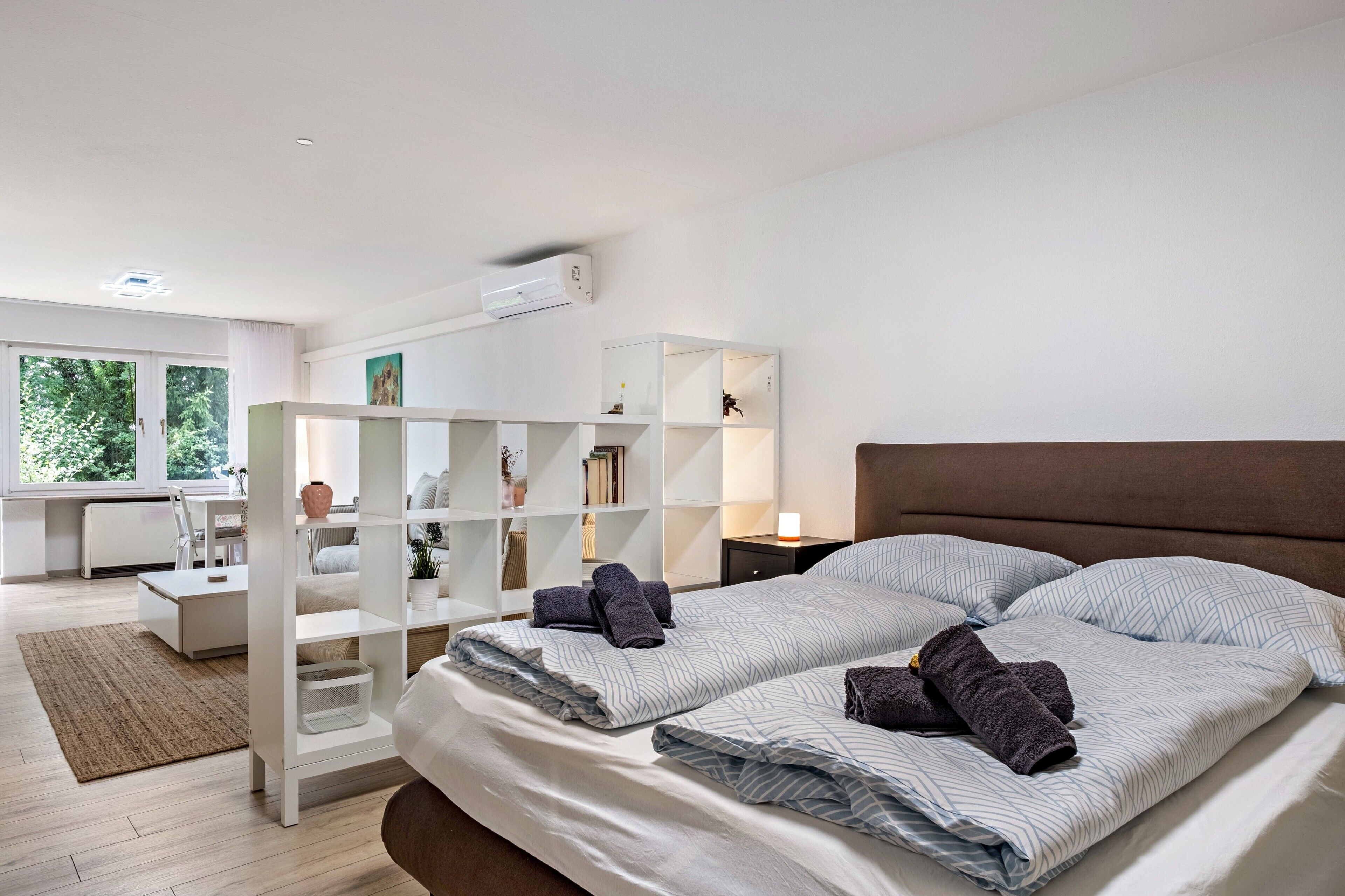 Une chambre moderne avec un grand lit, une étagère blanche et un bureau avec une chaise.