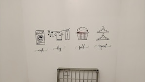 Un espace buanderie comprenant un lave-linge, un étendoir et un panier à linge plié.