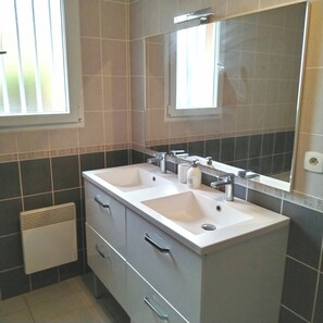 A bathroom with two sinks, a mirror, and a ventilation system.