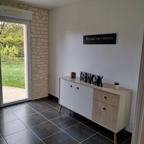 A room with a stone wall, a white cabinet with drawers, a sign on the wall, and a view of greenery outside.