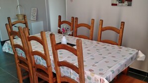 Un coin repas avec une table recouverte d’une nappe à pois, entourée de chaises en bois.