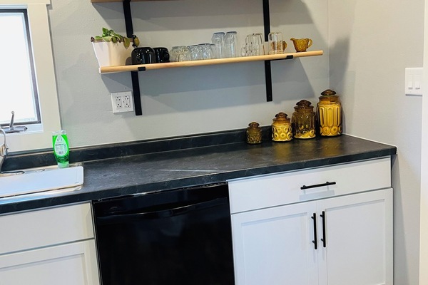 Modern kitchenette with open shelving, mini fridge, and sleek finishes