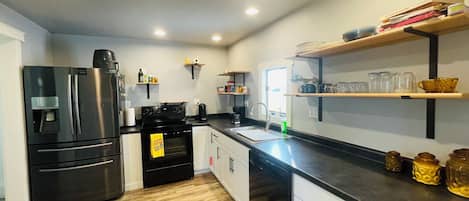 Una cocina moderna con un refrigerador de acero inoxidable, una estufa negra y piso de madera.