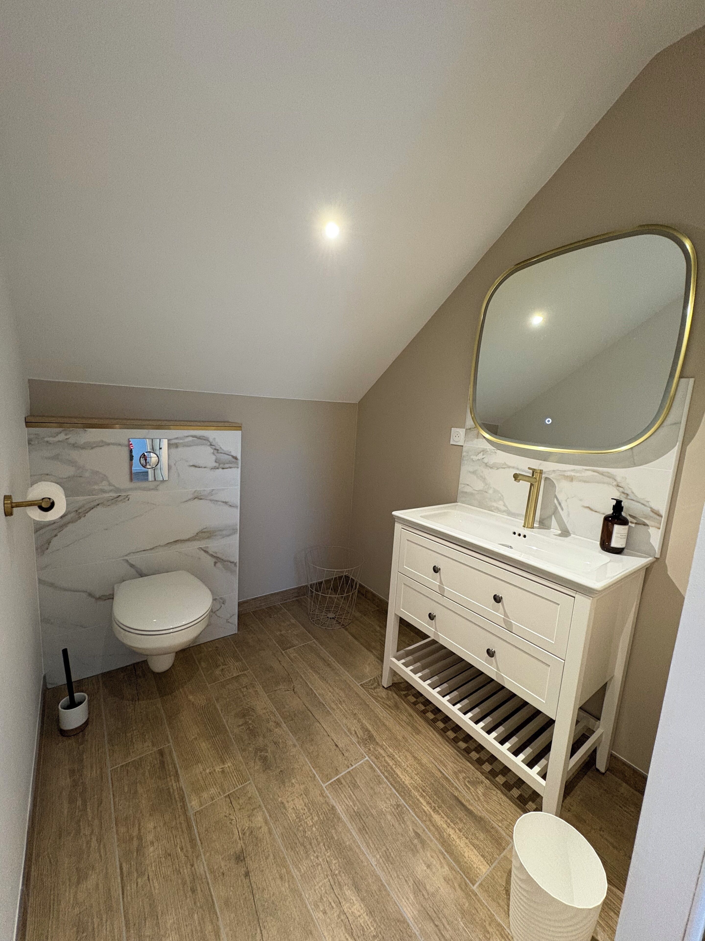Une salle de bain avec des toilettes, un lavabo et un miroir.