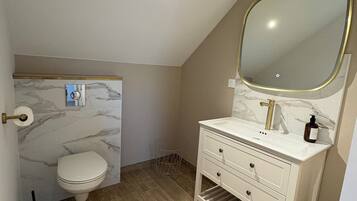Une salle de bain avec des toilettes, un lavabo et un miroir.