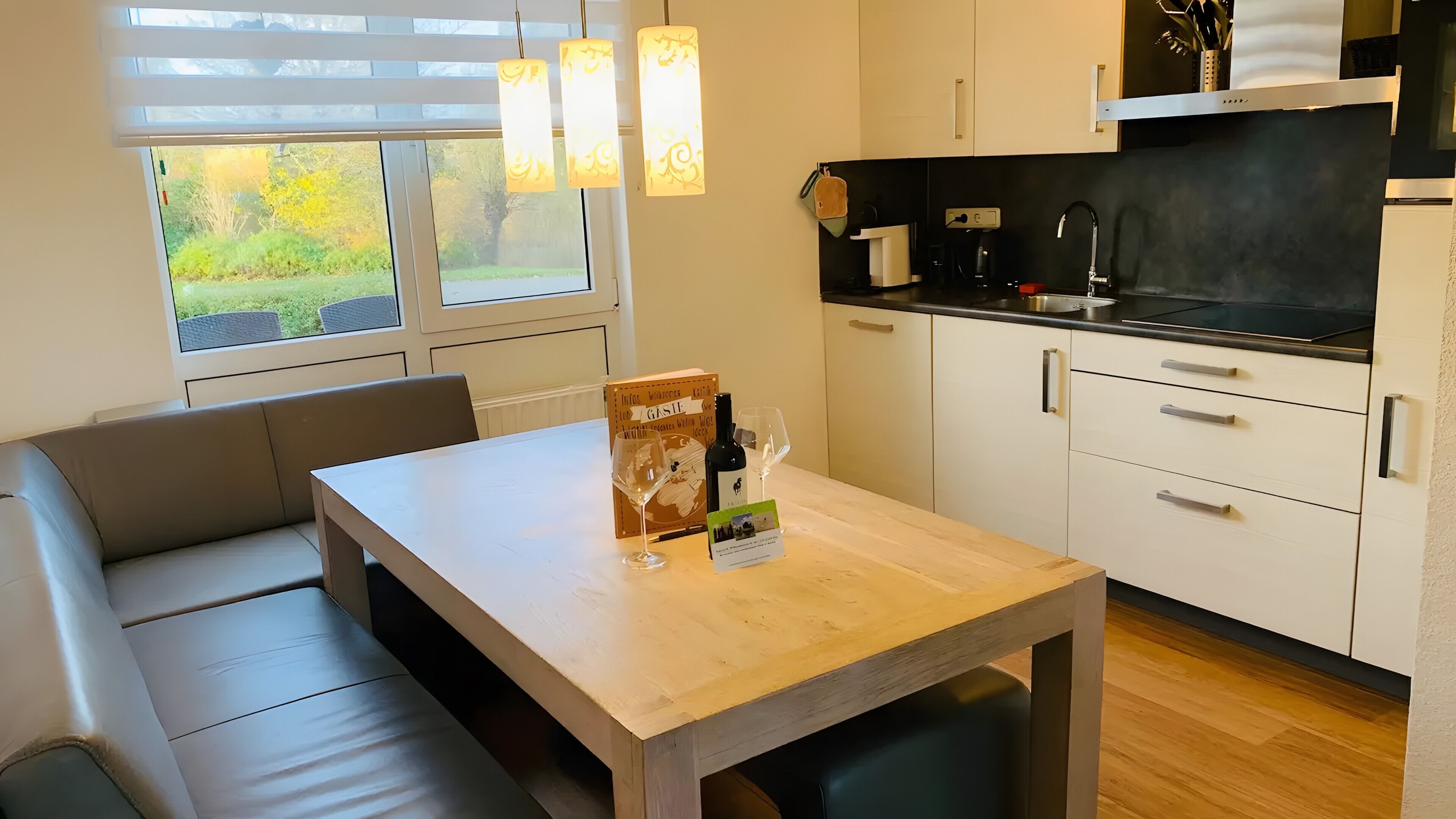 A modern kitchen with a dining area, including a table, chairs, and a sofa.
