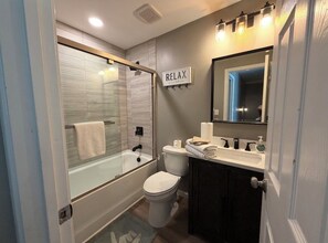 A bathroom with a glass-enclosed shower, a toilet, a sink, and a mirror. - Charming 4-bedroom house with AC in cozy Alabaster (Alabaster)