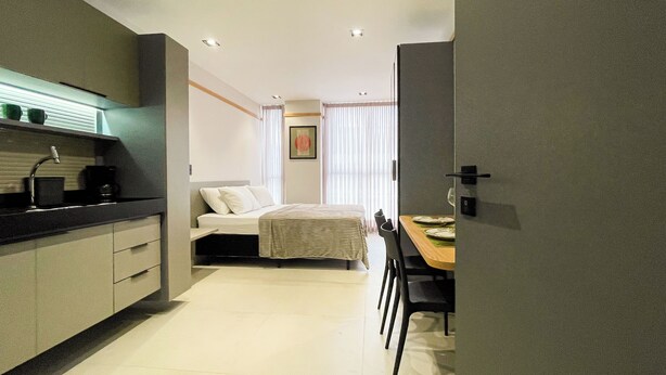 Una habitación de hotel moderna con kitchenette, una cama, zona de comedor y baño.