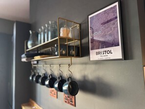 A wall-mounted rack with mugs and a framed map of Bristol. - Boho Rooms (Bristol)
