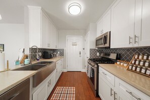 A modern kitchen with white cabinetry, stainless steel appliances, and a patterned backsplash. - Fabulous 3-bedroom deep lounging Pool house with AC & Arcade in vibrant Houston (Houston)