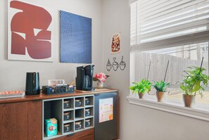 A room with a coffee station, artwork on the wall, and a window with plants. - Fabulous 3-bedroom deep lounging Pool house with AC & Arcade in vibrant Houston (Houston)