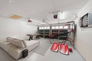 Een kamer met een bank, een dartbord, een tafelvoetbaltafel en een biljarttafel.