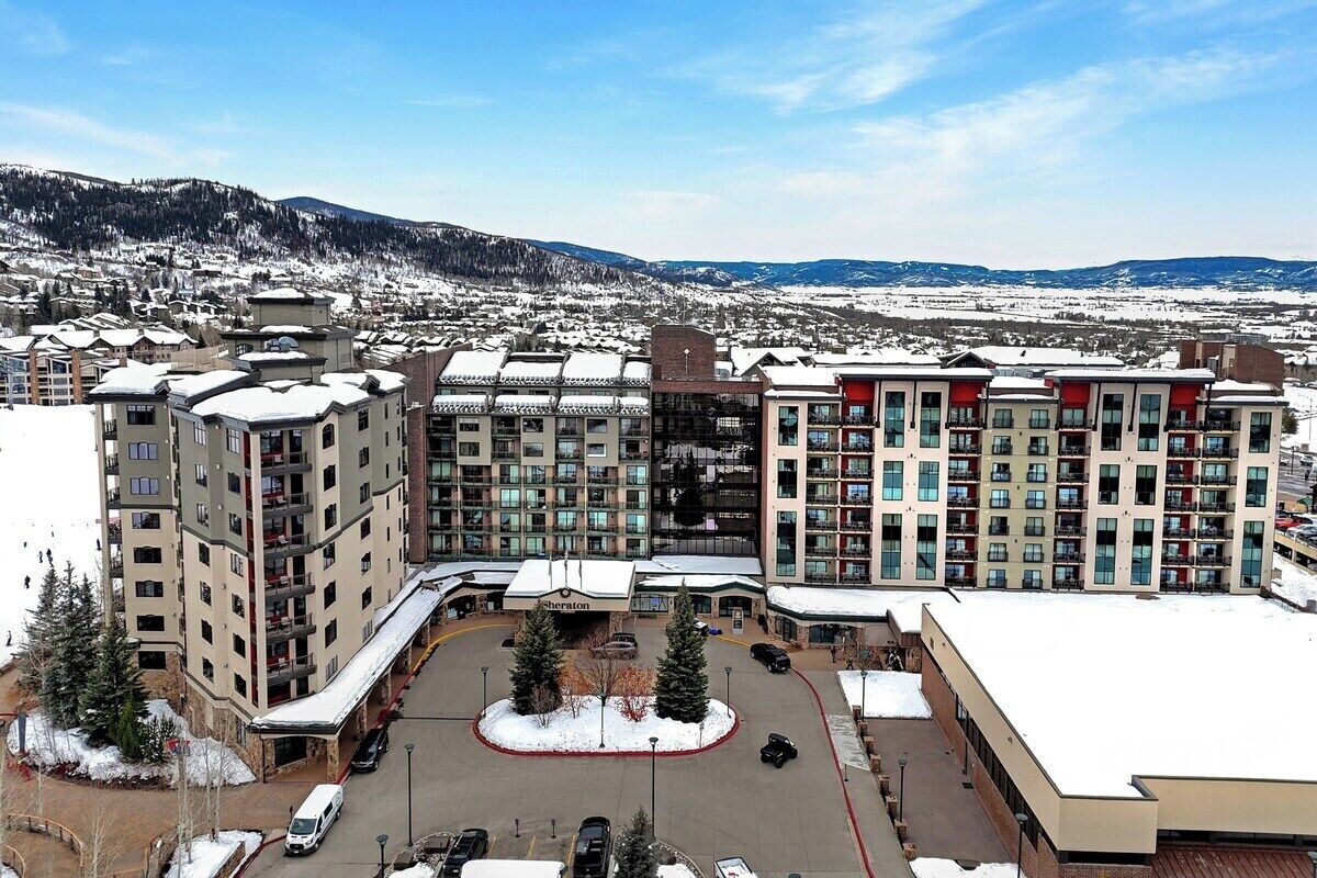 Ein mehrstöckiges Hotel mit Innenhof, umgeben von schneebedeckten Gebäuden und einer Bergkulisse.