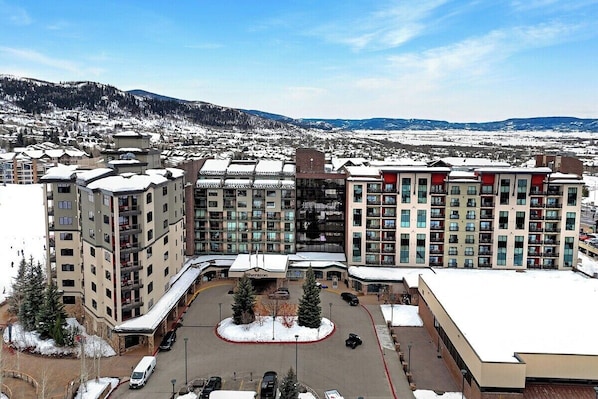 Een meerlaags hotel met een centrale binnenplaats, omringd door met sneeuw bedekte gebouwen en een bergachtige achtergrond.