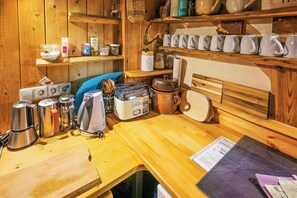 Eine Küche mit Holzschränken, einer Kaffeemaschine, einem Toaster, einem Wasserkocher und verschiedenen Küchenutensilien.