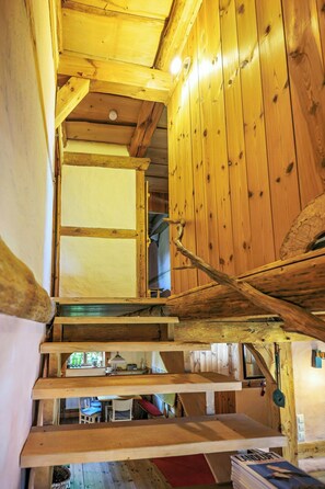 A wooden interior with a staircase leading to an upper level, a visible window, and a door with a wooden handle. - Eco-friendly farmhouse with a garden by the river (Zehrental)