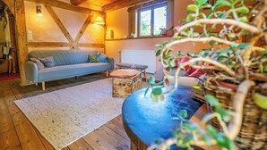 Una sala acogedora con un sofá, piso de madera, alfombra blanca y una planta.