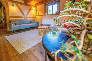 A cozy living room with a sofa, a wooden floor, a white rug, and a plant. - Eco-friendly farmhouse with a garden by the river (Zehrental)