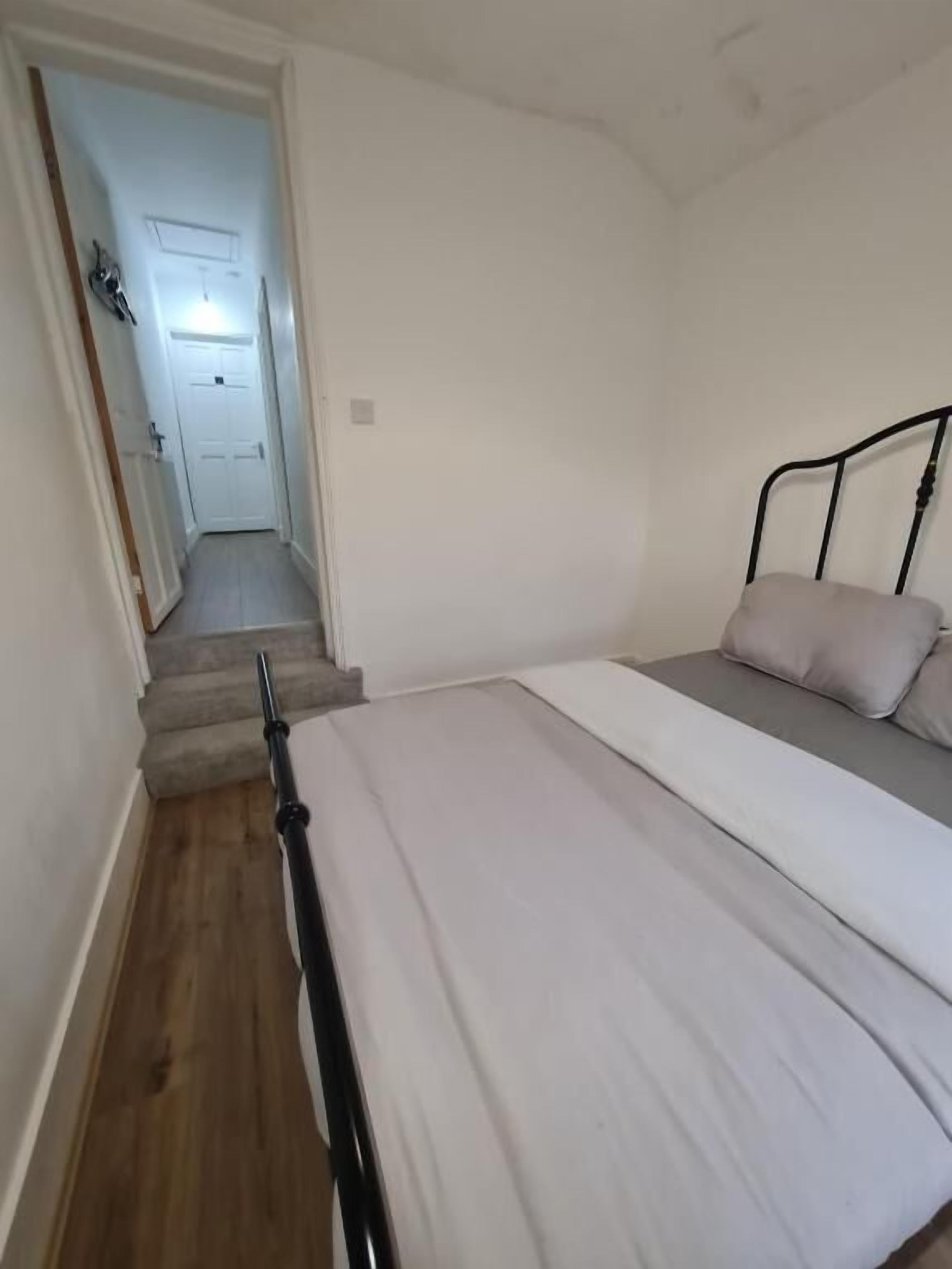 Une chambre à coucher avec un lit, une tête de lit en métal et un escalier menant à une autre pièce.