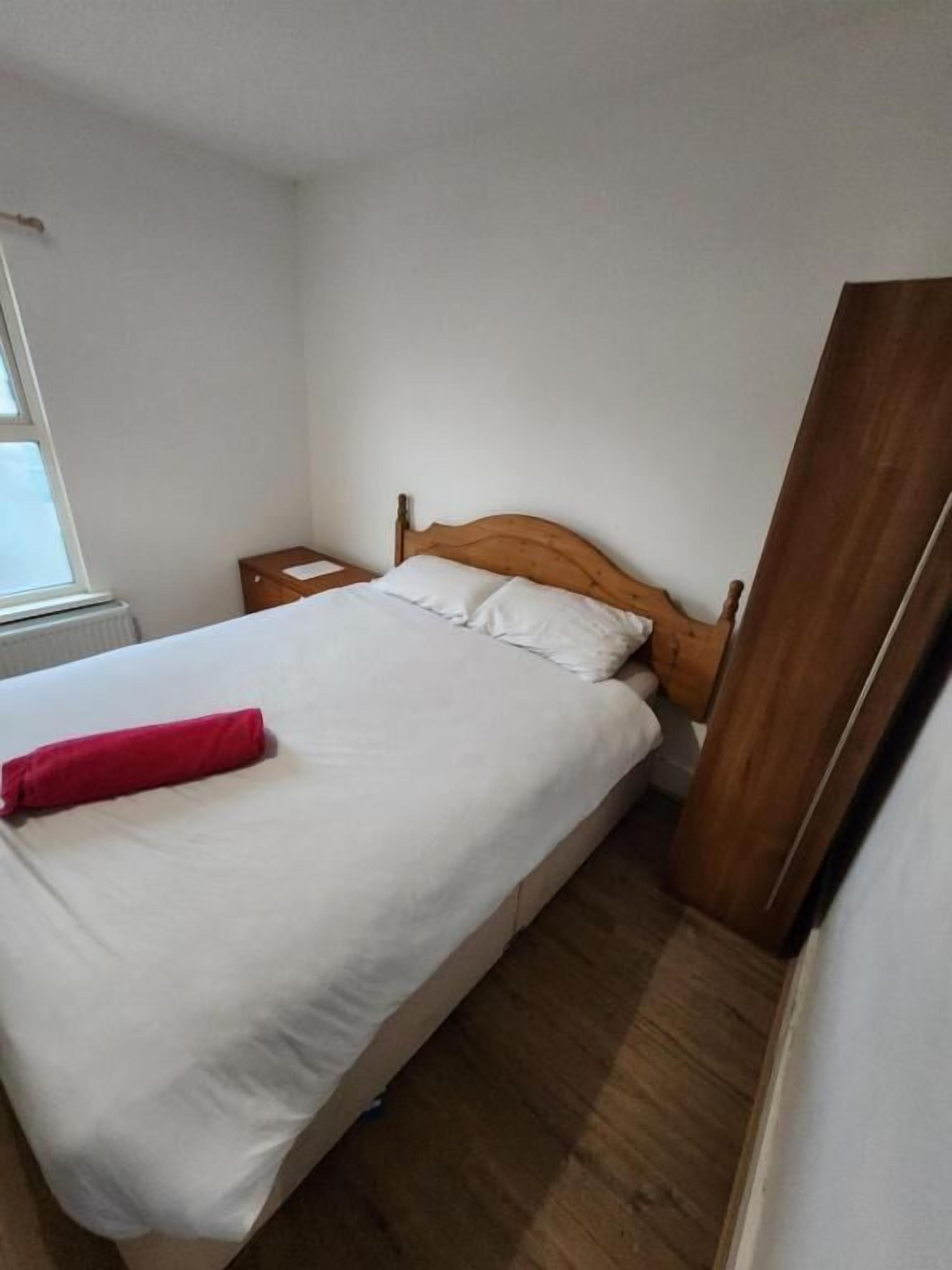 A single bed with a wooden headboard in a room with white walls and a wooden floor.