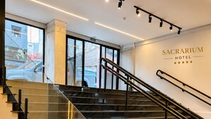 Una escalera moderna en un hotel con barandillas de vidrio y un letrero que indica el Hotel Sacrarium.