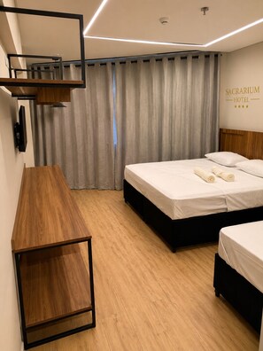 Una habitación de hotel con una cama, un escritorio y un televisor montado en la pared.