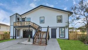 A two-story house with a front porch, a staircase, and a garage. - Holds 8 · Pool · 3BR/2BA Upper Duplex Peacock Horse Beach Nearby Out City Life (Galveston)