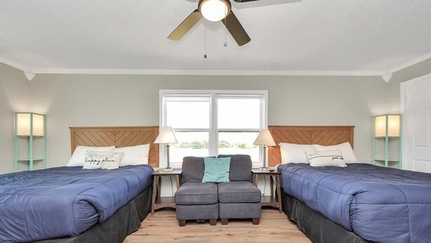 A hotel room with two beds, a sofa, and a ceiling fan. - Holds 8 · Pool · 3BR/2BA Upper Duplex Peacock Horse Beach Nearby Out City Life (Galveston)