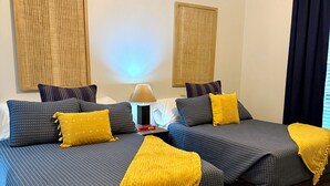 Et hotelværelse med to senge, et natbord, en lampe og et vindue med gardiner.