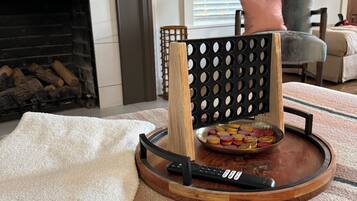 A wooden tray with a remote control and a bowl of colorful coasters on a textured rug.