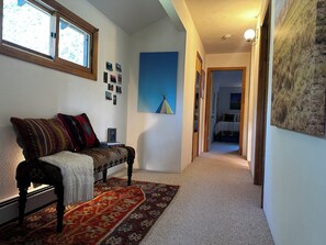 A hallway with a sofa, a patterned rug, and a painting on the wall.