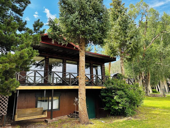 A cabin with a wooden deck, a covered porch, and a green door.