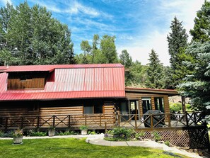 A log cabin with a red metal roof, a porch, and a deck. - Whispering Waters Retreat (South Fork)