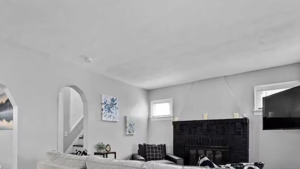 A modern living room with a grey sofa, a fireplace, and a television mounted on the wall.