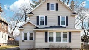 A two-story house with a gabled roof, a front porch, and a visible front yard.