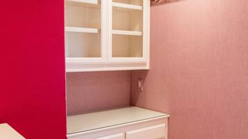 A room with a built-in white shelving unit against a red wall, a beige carpet, and a decorative border on the wall.