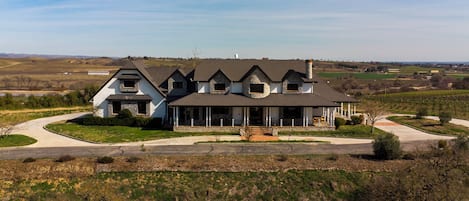 Ein großes, zweistöckiges Haus mit Steinaußenwand, zahlreichen Fenstern und einer Veranda.